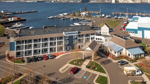 A marina with boats docked, a building with a sign reading "Port Pilot Marine Institute," and a parking lot with several cars. - Park Point Marina Inn (Duluth)