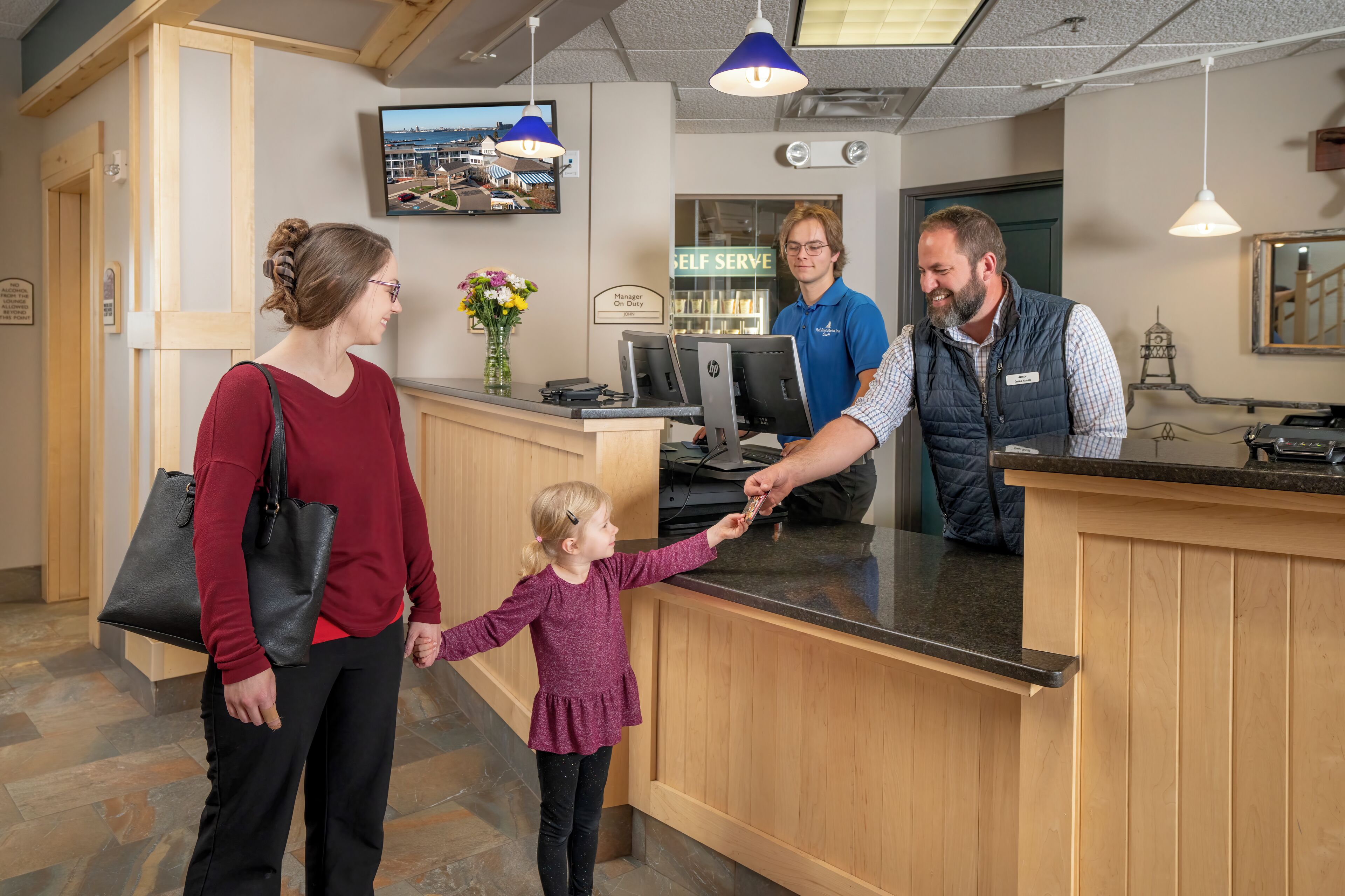 A reception area with a wooden counter, a TV mounted on the wall, and a 'Self Serve' sign.