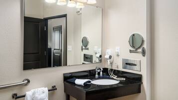 A bathroom with a large mirror, a black sink, a towel rack, and a hairdryer.