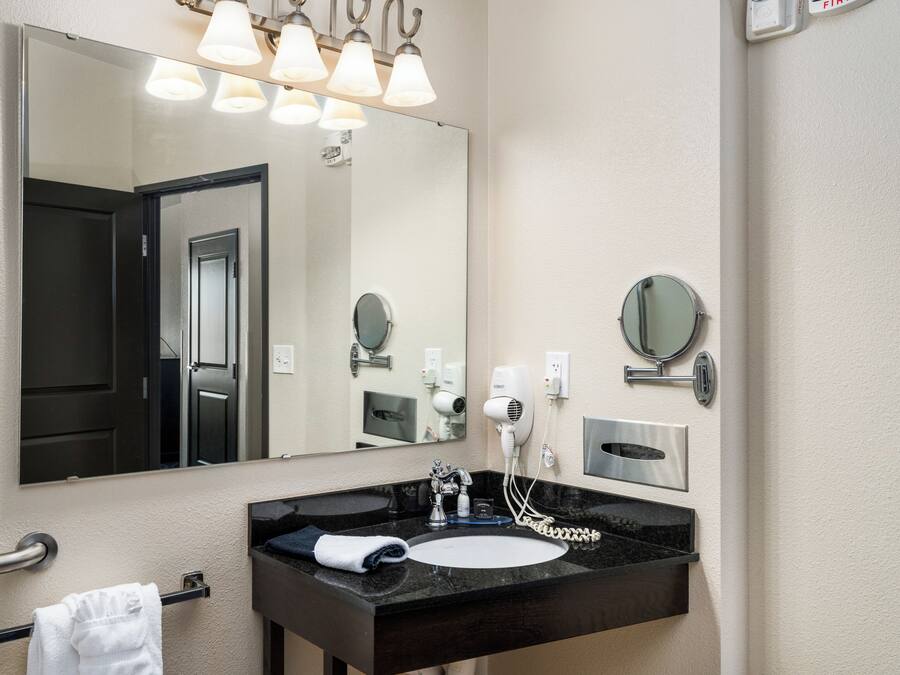 A bathroom with a large mirror, a black sink, a towel rack, and a hairdryer.