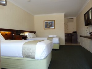 A hotel room with two beds, a desk with a telephone, a painting on the wall, and a television mounted on the wall. - The Miners Rest Motel (Somerville)
