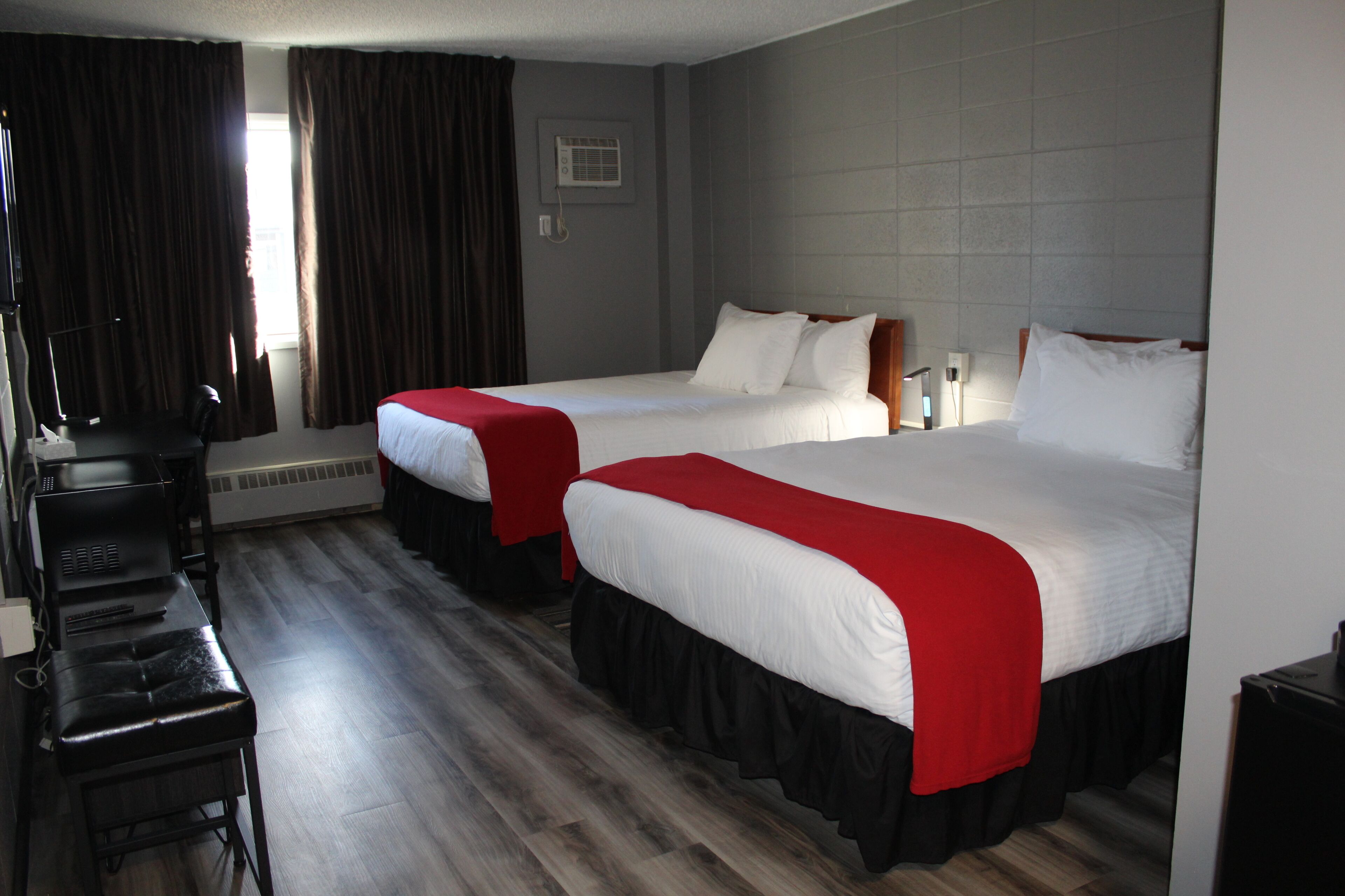 A hotel room with two beds, a desk, and a chair.