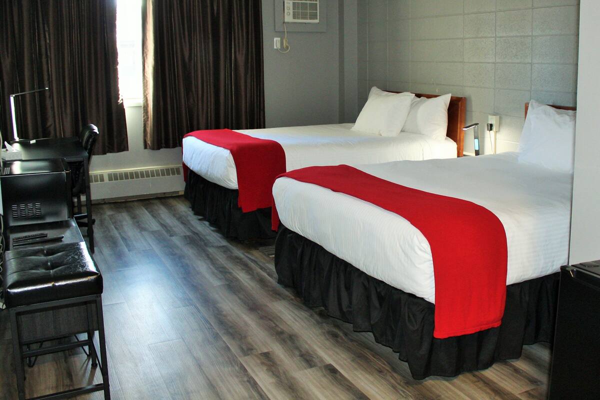 A hotel room with two beds, a desk, and a chair.