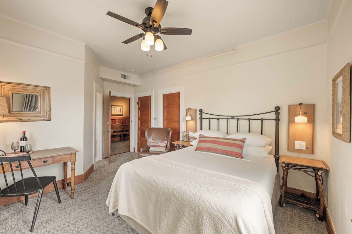 Une chambre d’hôtel équipée d’un lit, d’un bureau, d’une chaise et d’un ventilateur de plafond.