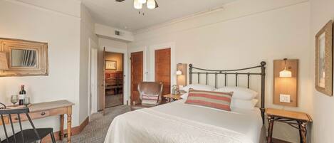 Una habitación de hotel con cama, escritorio, silla y ventilador de techo.