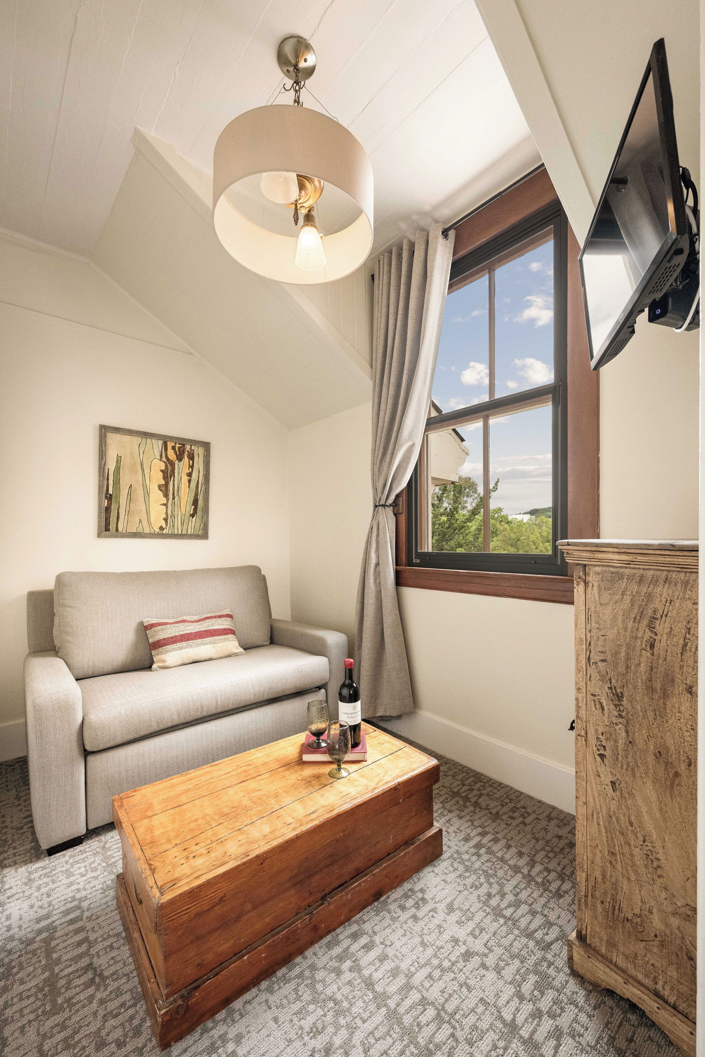 Una habitación acogedora con un sofá, un aparador de madera, una ventana con vistas y una lámpara en el techo.