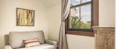 Una habitación acogedora con un sofá, un aparador de madera, una ventana con vistas y una lámpara en el techo.