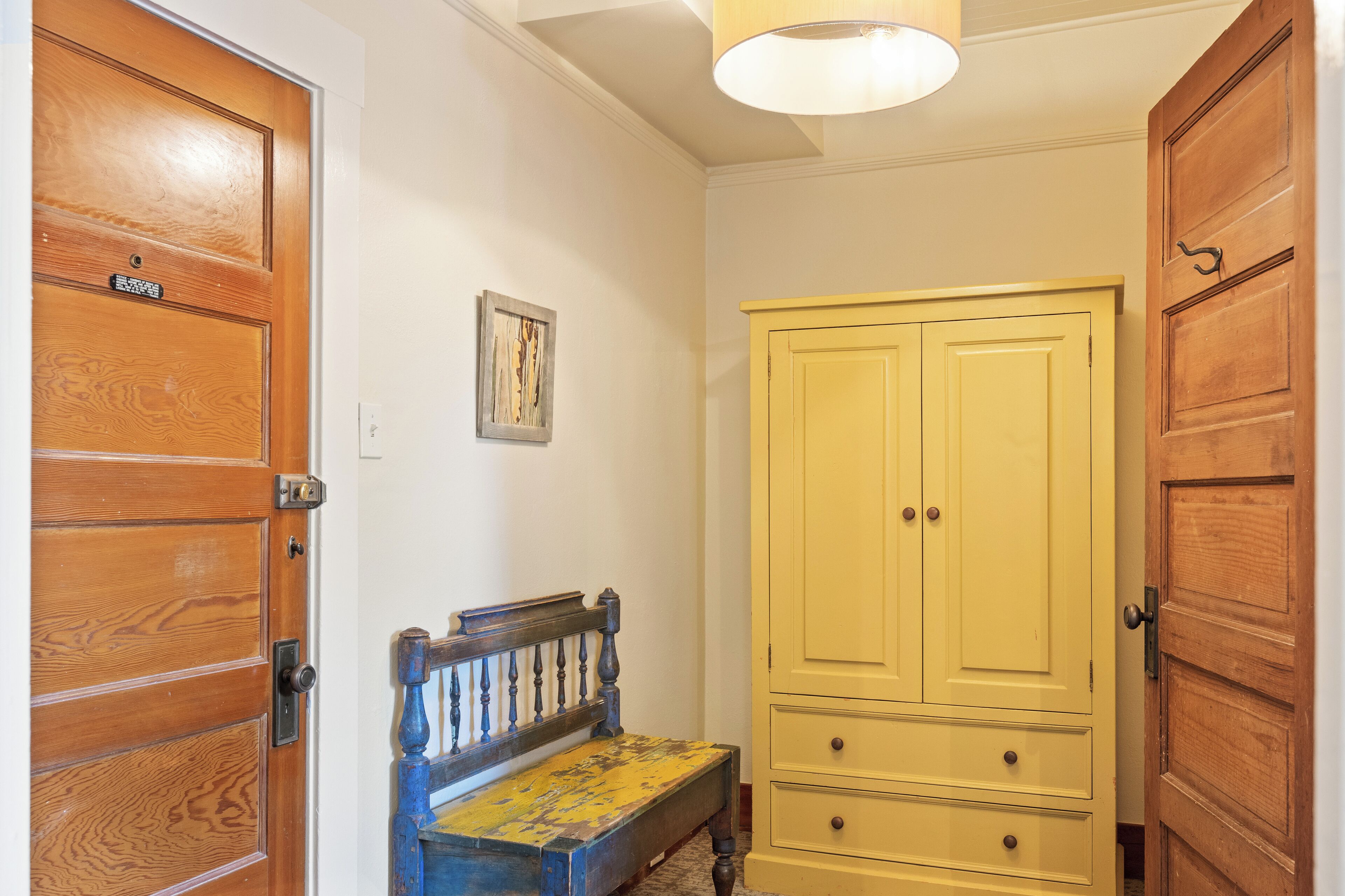 Un pasillo con puertas de madera, un banco y un armario amarillo.