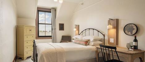 A bedroom with a bed, a desk, a chair, a wardrobe, and a ceiling fan.