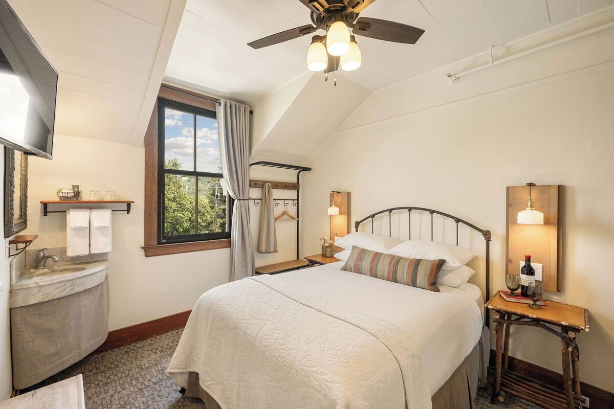 Une chambre à coucher avec un lit, une table de chevet, une lampe et un ventilateur de plafond.