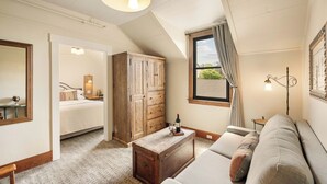 Una habitación acogedora con una cama, un cofre de madera, un sofá y una ventana con cortinas.