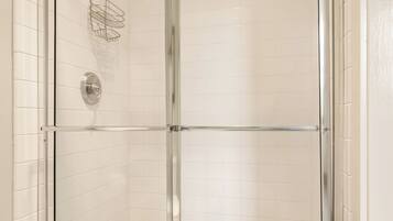 A glass-enclosed shower with a tiled floor and a metal showerhead.