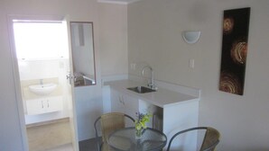 Una cocina compacta con un lavamanos, una pequeña mesa de comedor con dos sillas y un espejo.