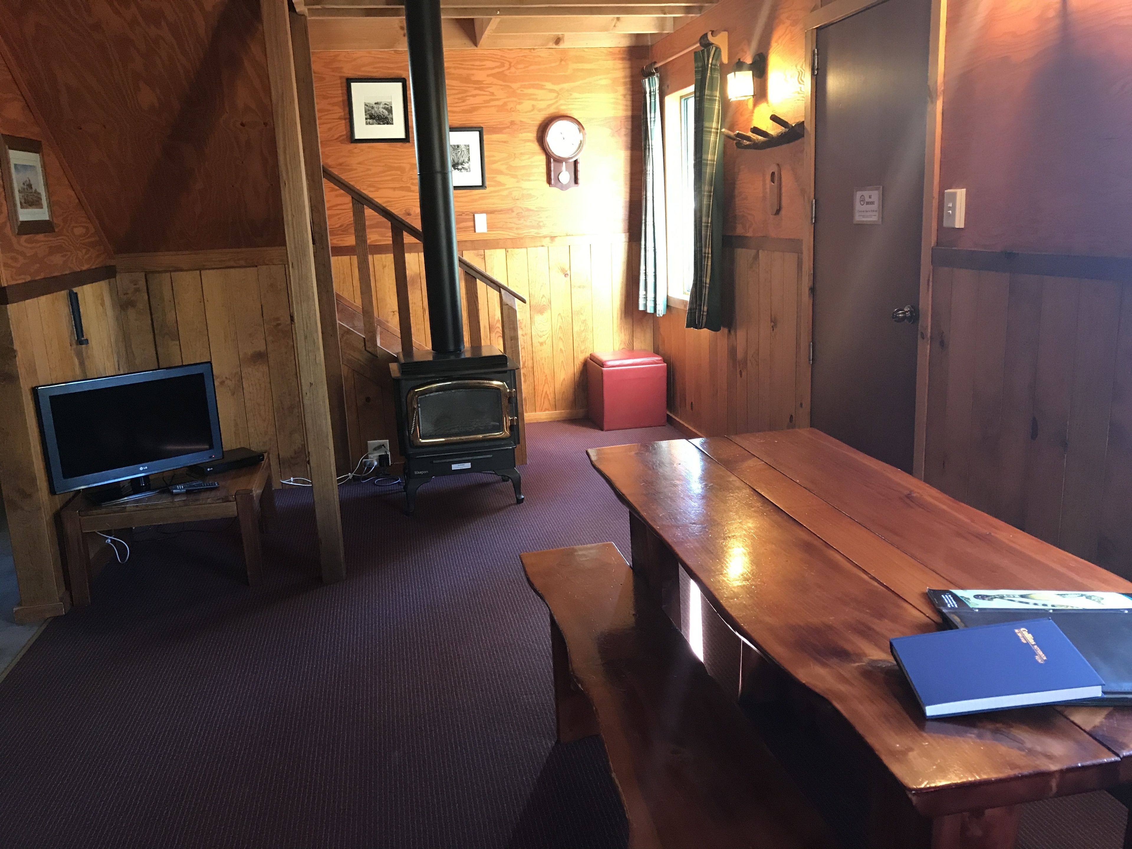 Una habitación acogedora con detalles de madera, una chimenea, un televisor y un banco con un libro.