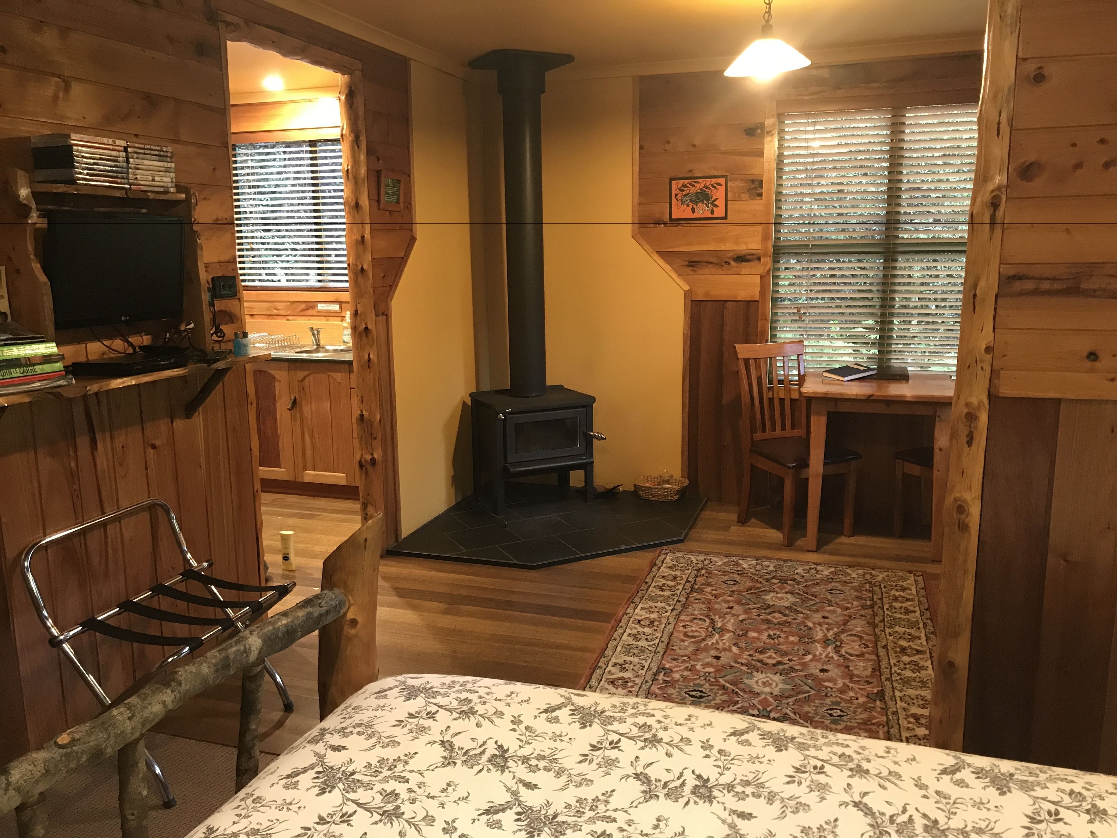 A cozy cabin interior with a wooden interior, a fireplace, a dining area, and a television.