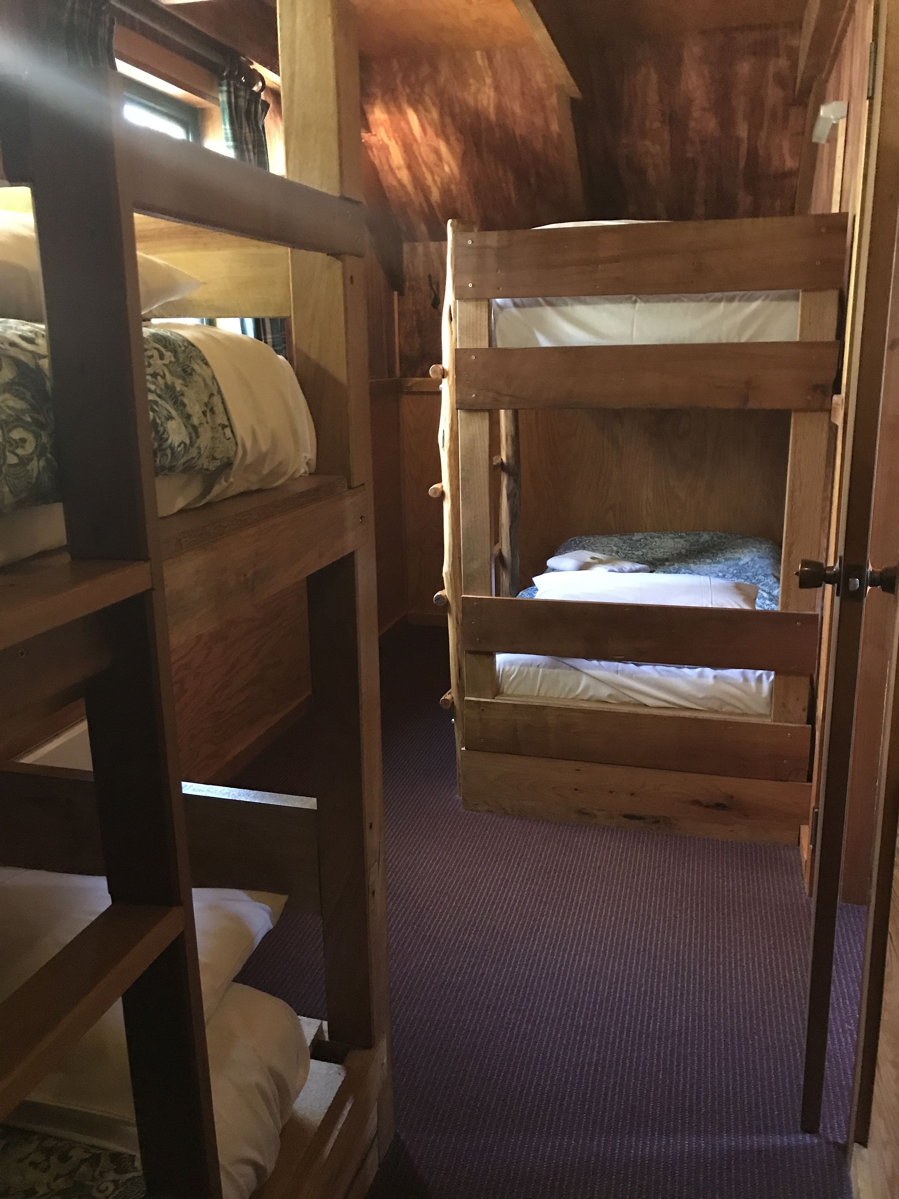 A wooden bunk bed room with a purple carpet.