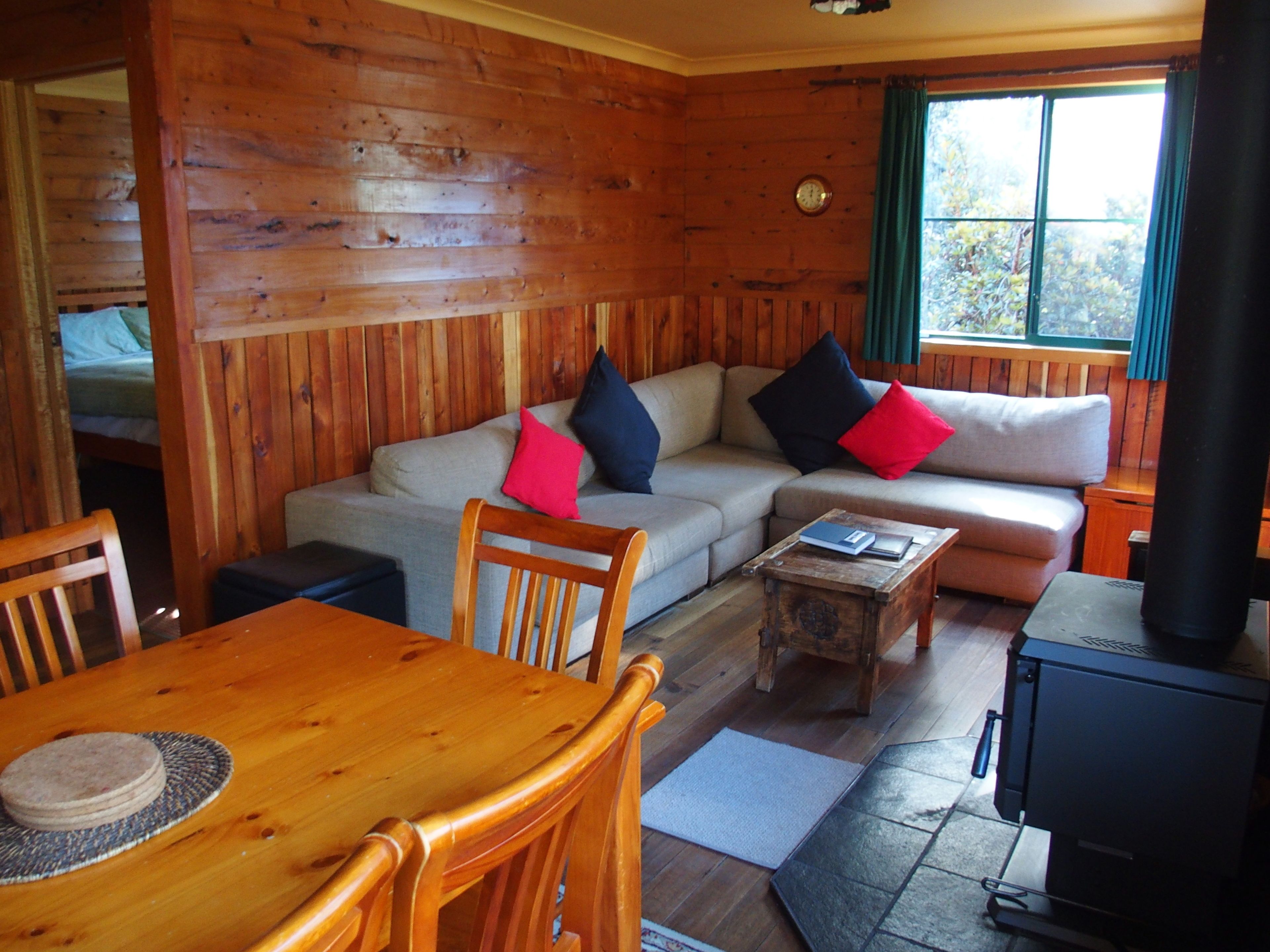 L’intérieur d’un chalet en bois, avec un canapé, des fauteuils, une table à manger et une cheminée.
