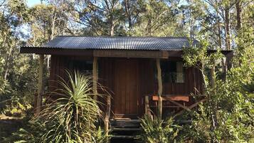 A rustic wooden building with a corrugated metal roof, surrounded by dense foliage.