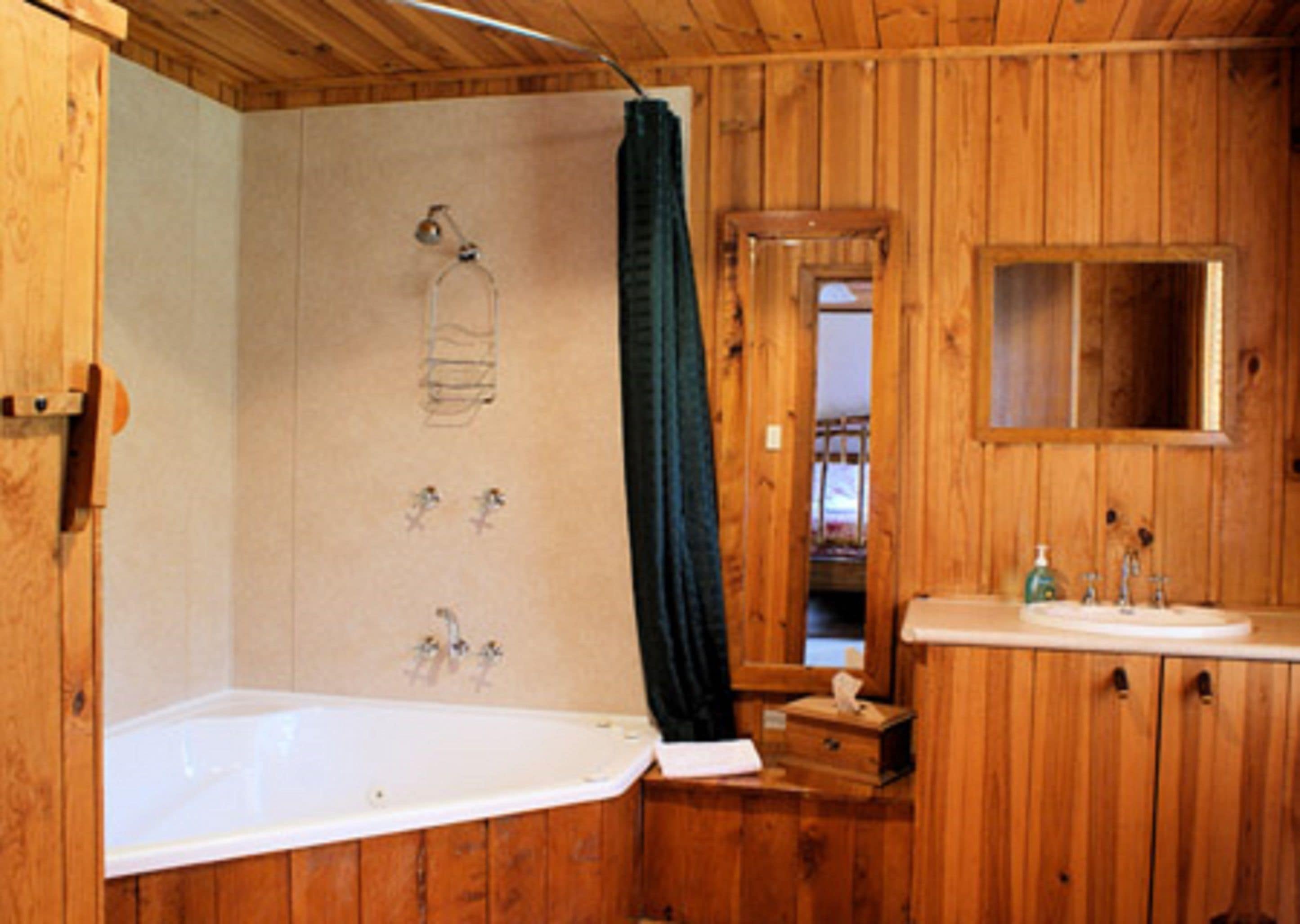 Un baño rústico con bañera, lavabo y espejo.