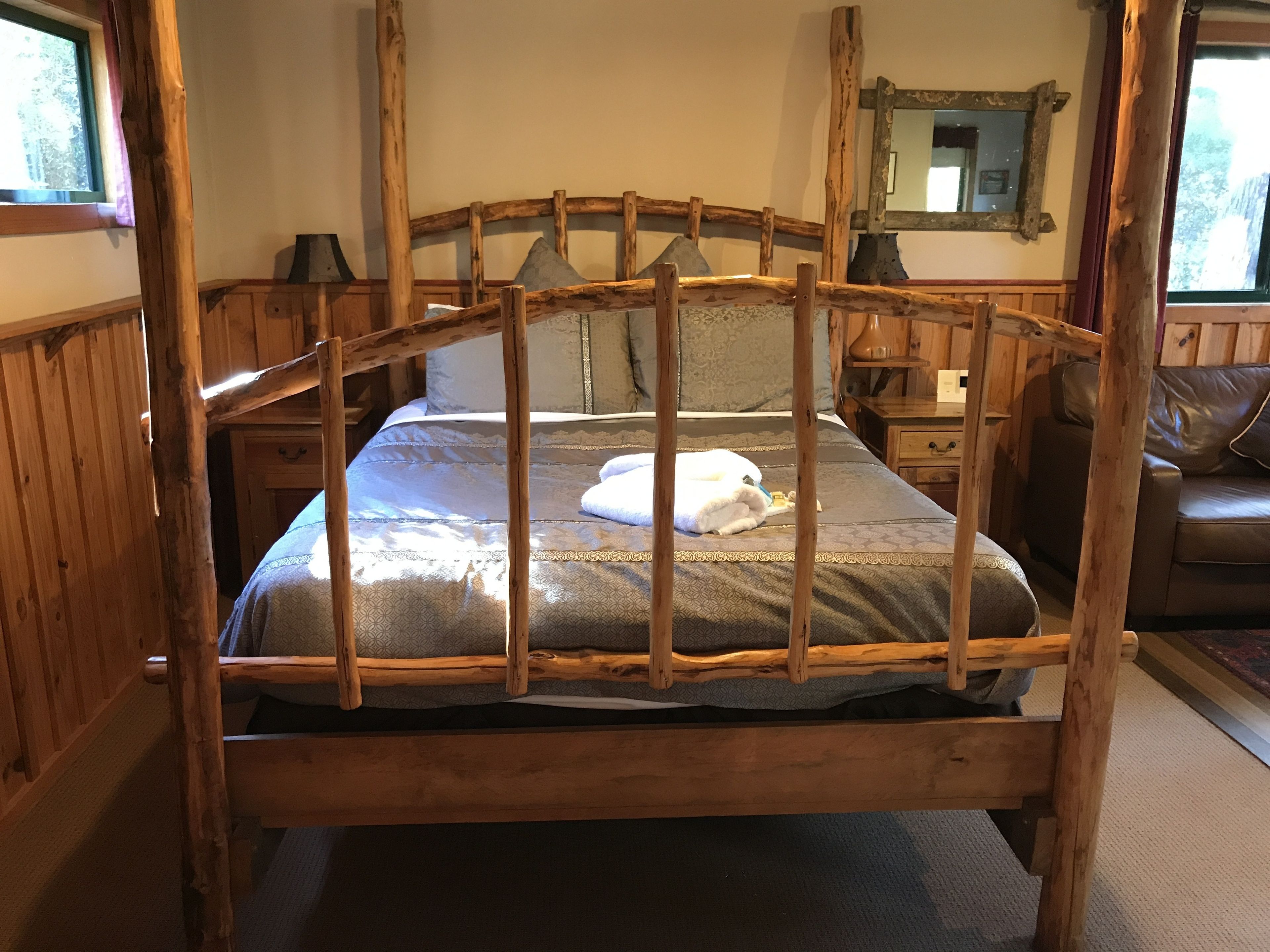 Ein hölzernes Himmelbett mit einem gemusterten Bettbezug und einem weißen Handtuch.