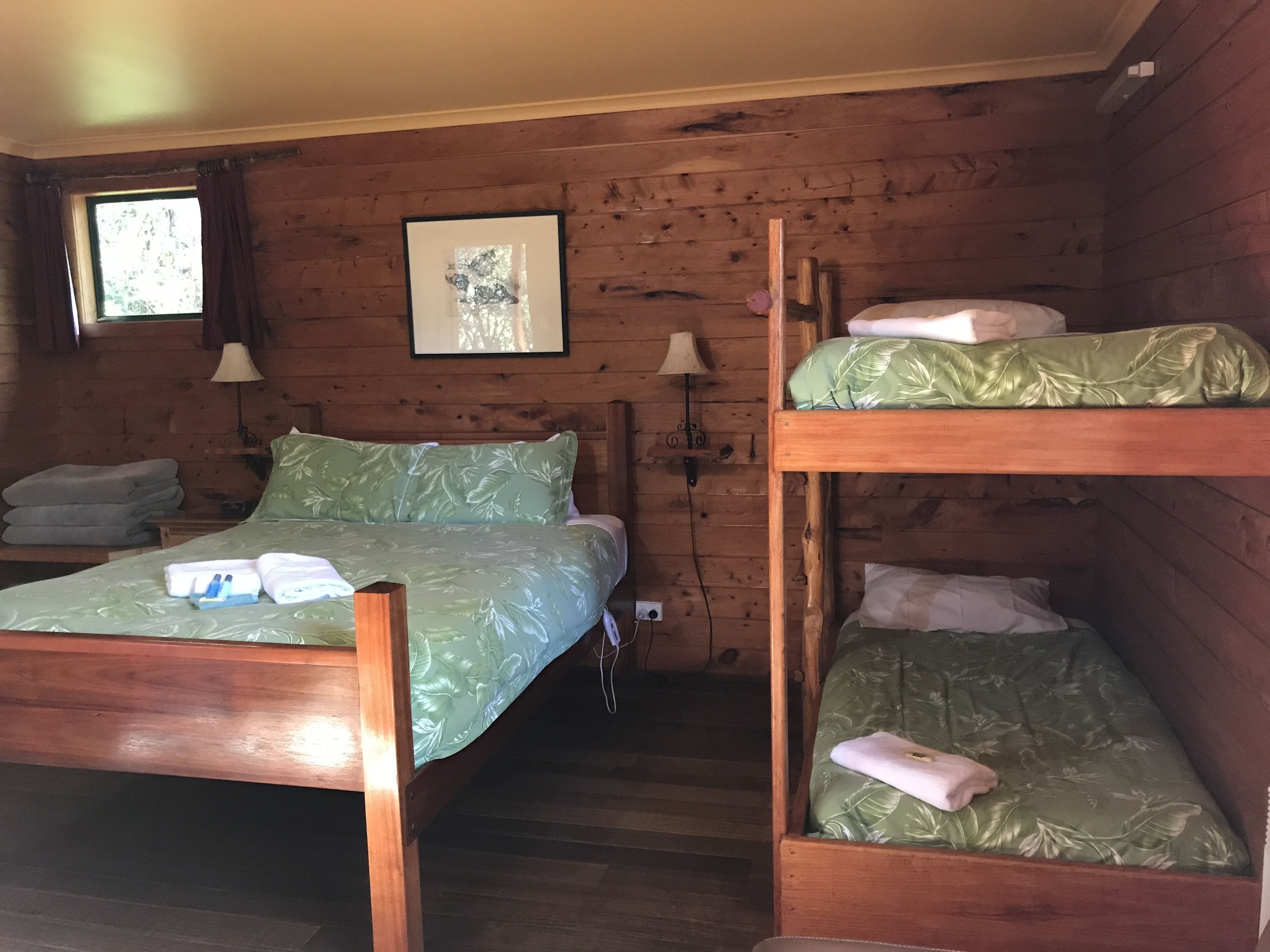 A cabin-style room with two bunk beds, a wooden floor, and a framed picture on the wall.