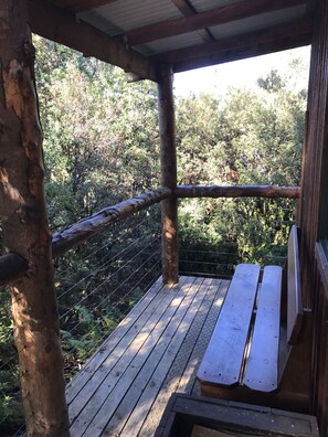 A wooden deck with a bench, surrounded by a metal fence and trees. - Cradle Highlander (Cradle Mountain)