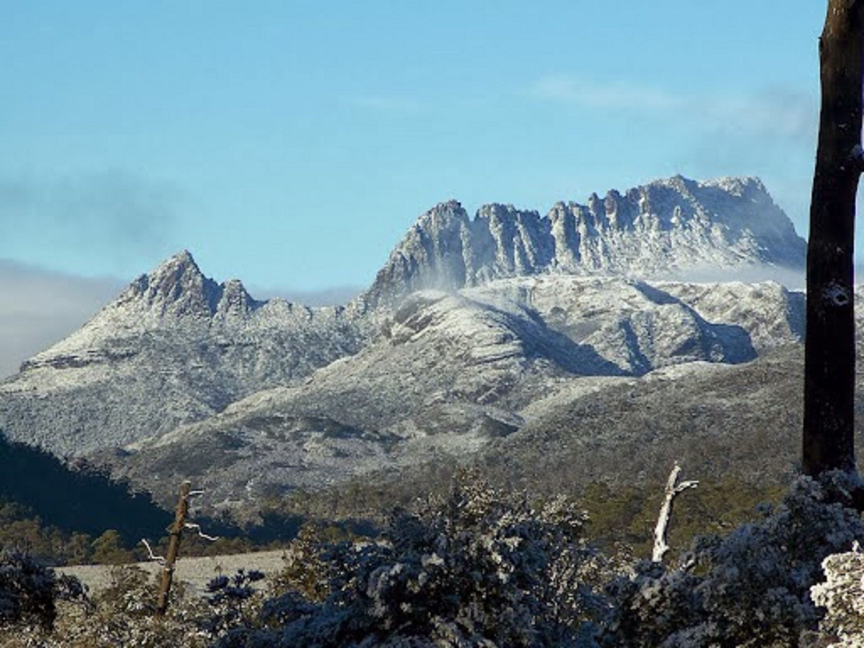 Un paisaje montañoso con picos nevados y cielo despejado.