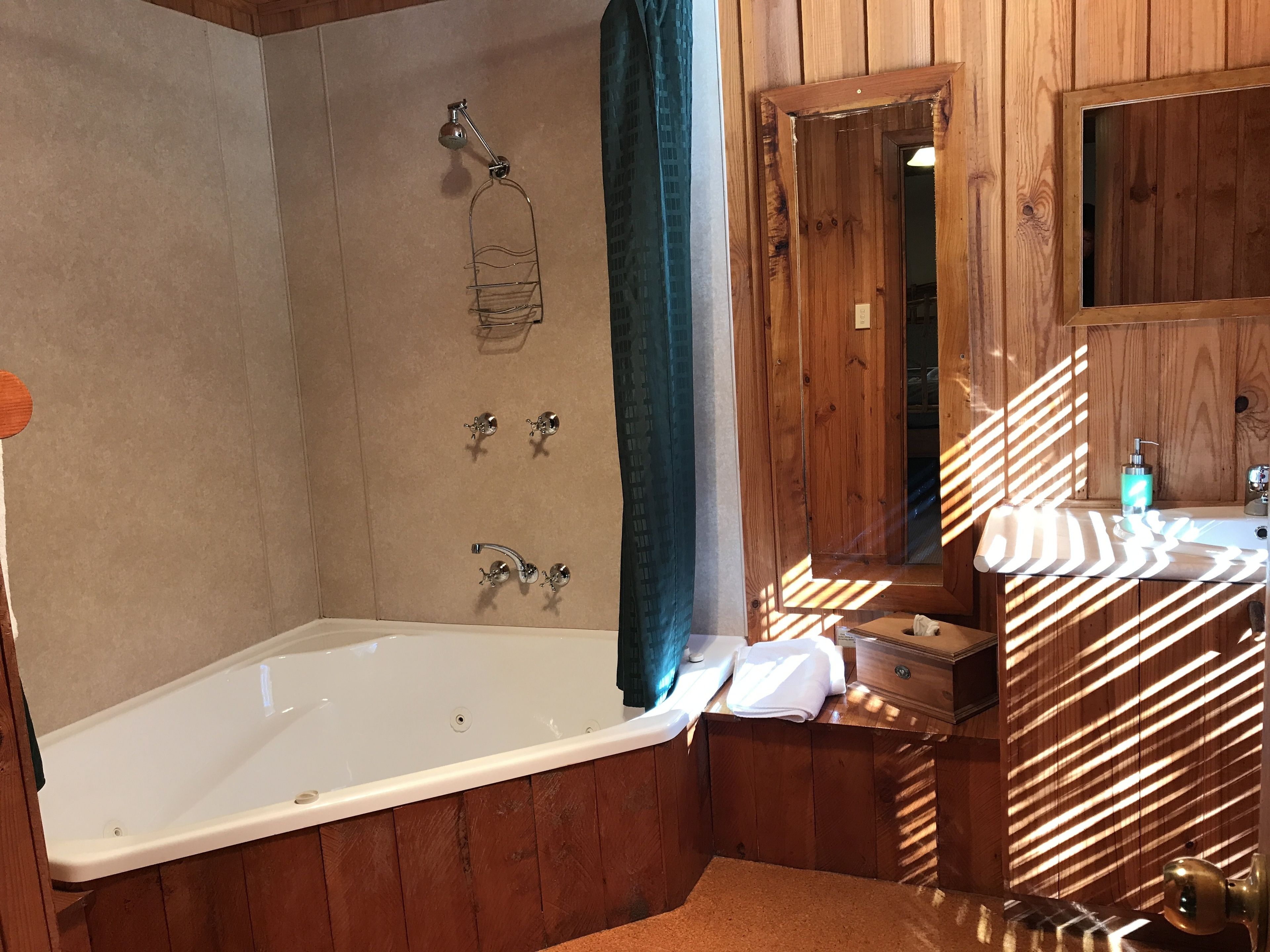 A wooden bathroom with a bathtub, a shower, and a vanity with a mirror.