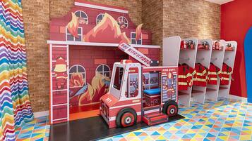 A colorful play area with a fire truck and firefighter figures.