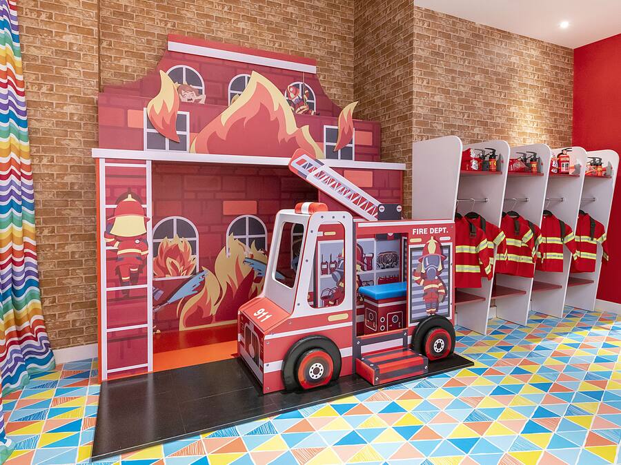 A colorful play area with a fire truck and firefighter figures.
