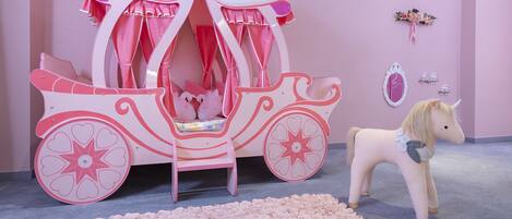 Una habitación con temática rosa, con un carruaje decorativo y un caballo de juguete.