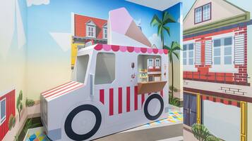 A colorful ice cream truck in a vibrant, cartoon-style setting with a house and palm trees in the background.