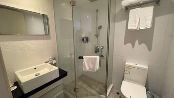 A modern bathroom with a glass-enclosed shower, a white sink, and a toilet.