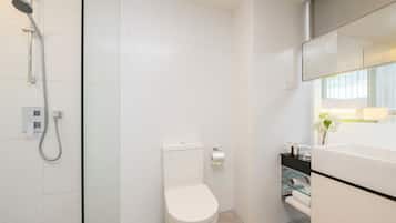 Un baño moderno con cabina de ducha de vidrio, inodoro blanco y tocador con espejo.