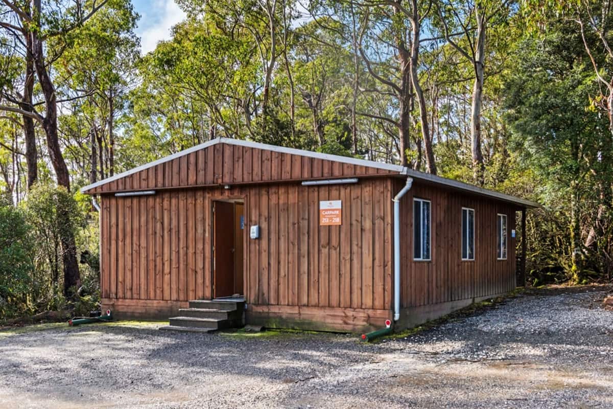 A wooden cabin with a sign reading "CAMPARE 23-218" in a forested area.