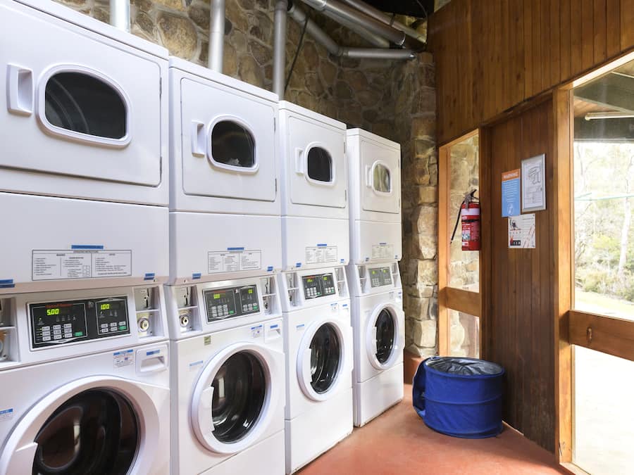 A laundry facility with multiple washing machines and a blue trash bin.