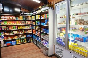 A grocery store interior with shelves stocked with various food items and a refrigerated section.