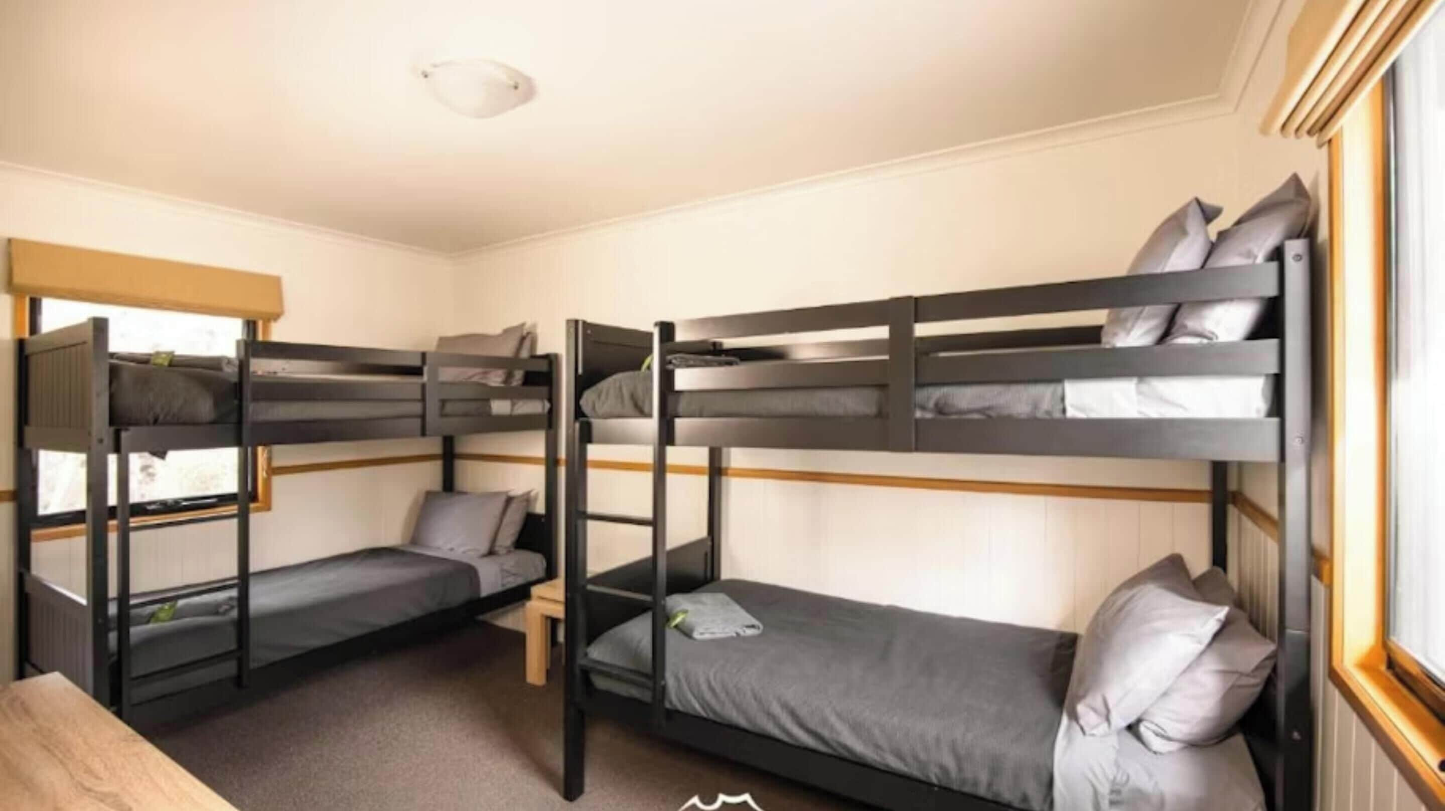Una camera con letto a castello, finestra, scrivania e termosifone.
