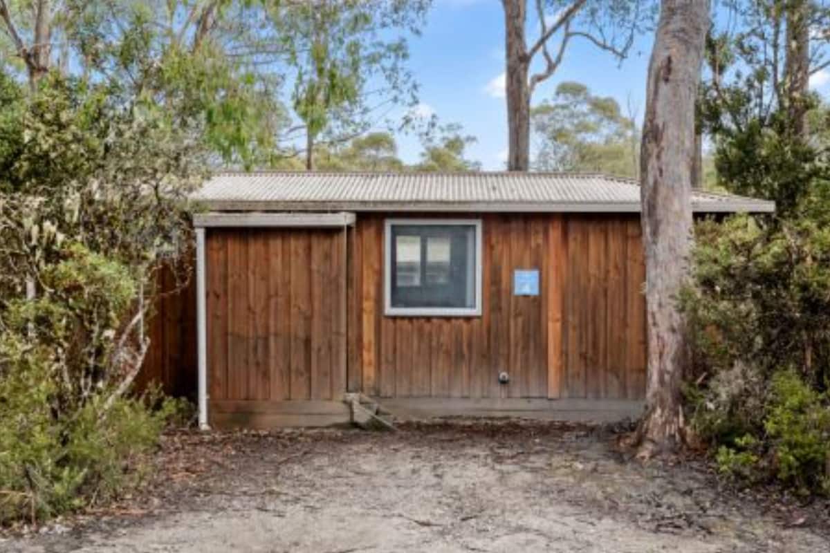 A wooden cabin with a metal roof, a window, and a door.