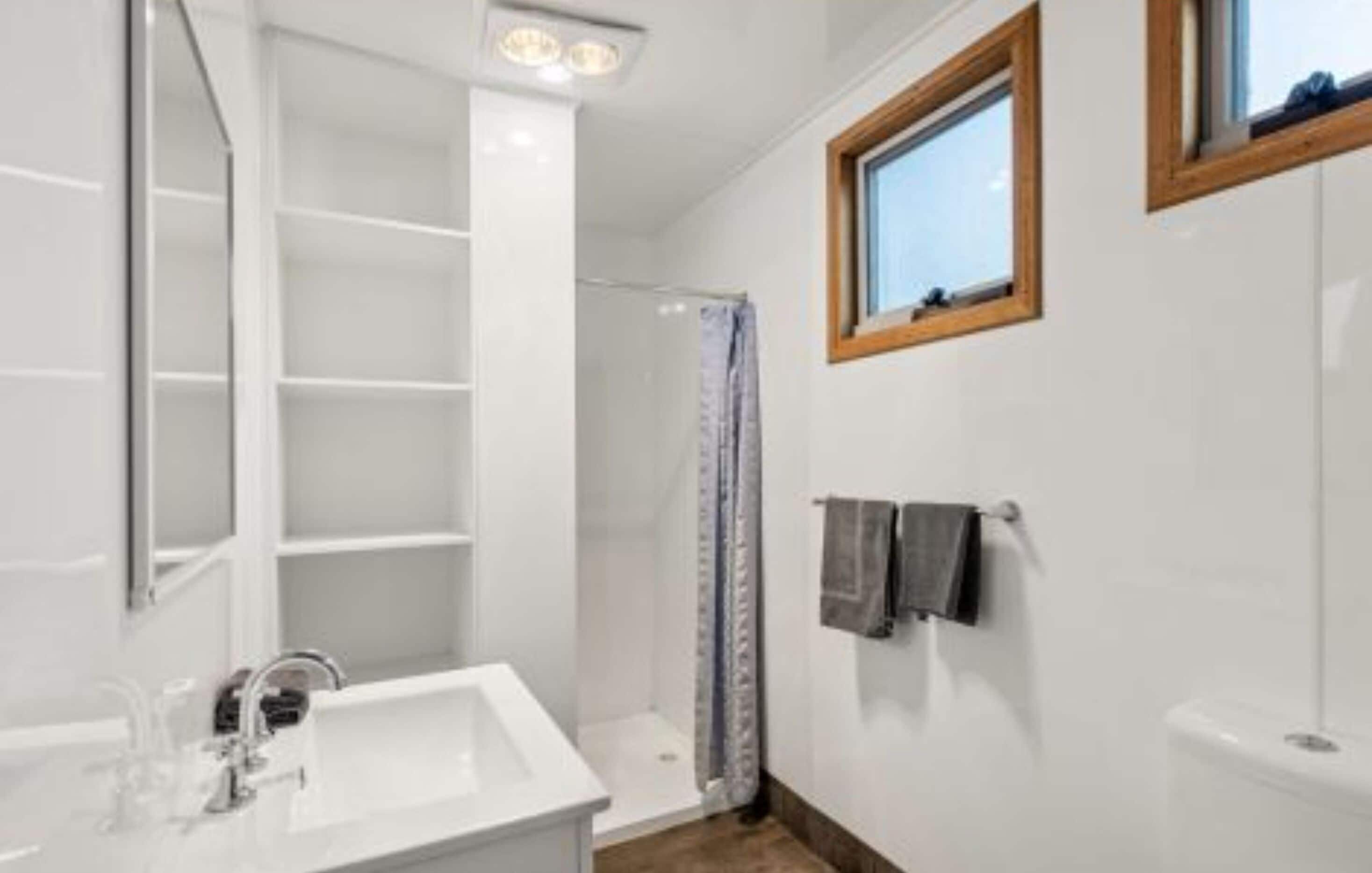 A bathroom with a white sink, a shower, and a window.