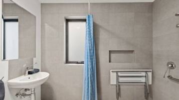 Une salle de bain moderne avec un lavabo blanc, un porte-serviettes et un espace douche.
