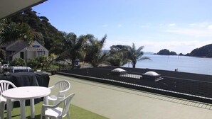 A terrace with a table and chairs, overlooking a body of water and a hilly landscape. - Bayview Motel (Paihia)