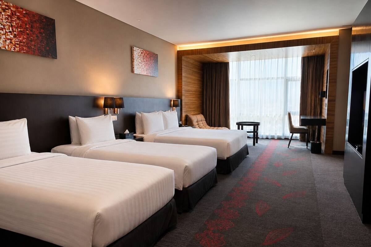 A hotel room with two beds, a desk, a chair, and a TV.