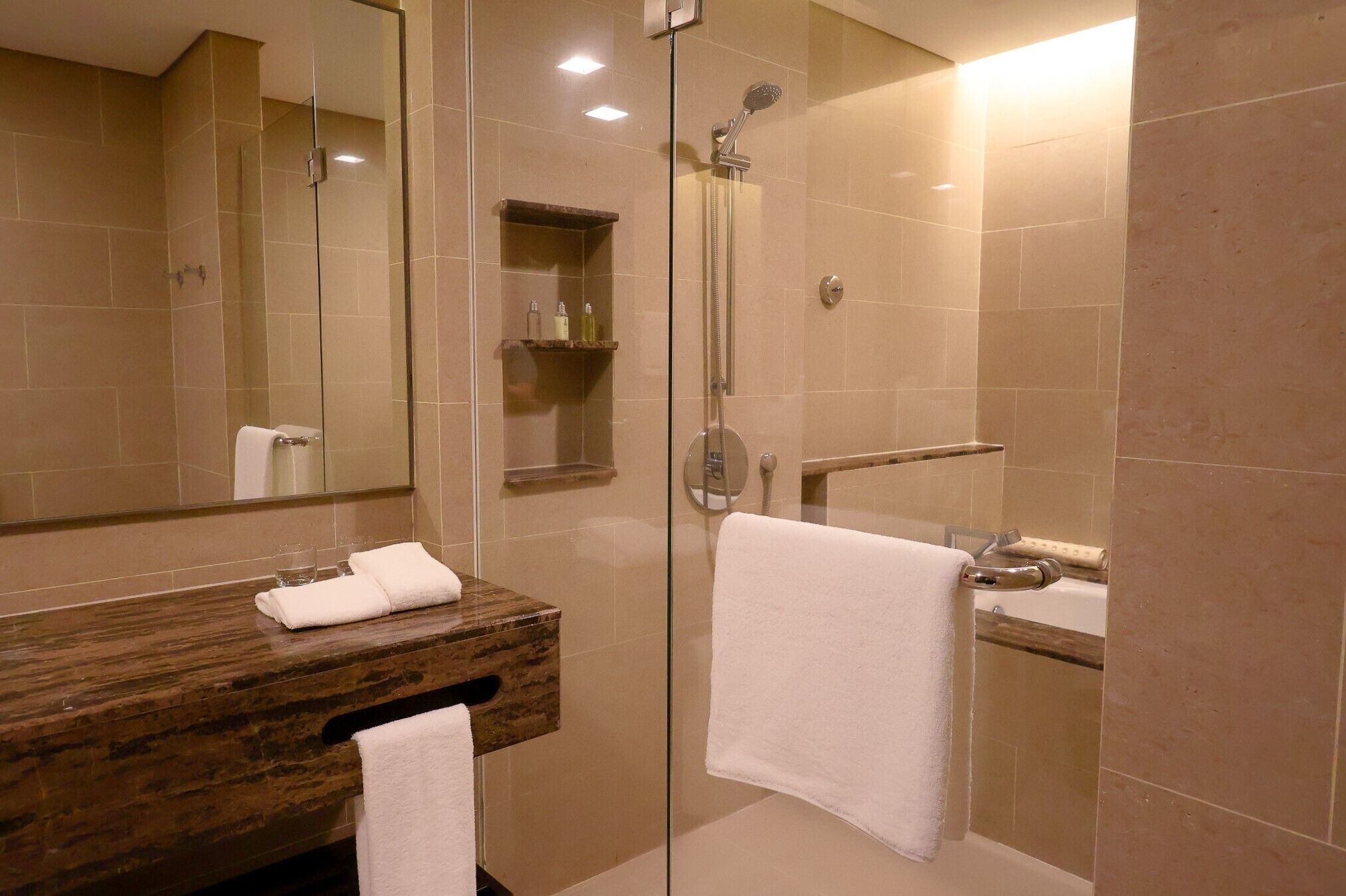 A modern bathroom with a glass-enclosed shower, a wooden vanity, and a large mirror.