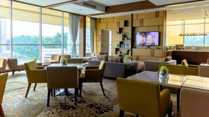 A modern hotel room with a large window, a sofa, a dining table, and a TV. - Grandis Hotel (Kota Kinabalu)