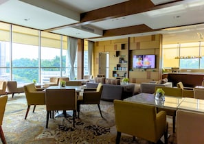 A modern hotel room with a large window, a sofa, a dining table, and a TV. - Grandis Hotel (Kota Kinabalu)