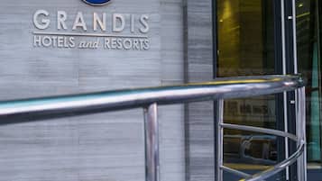A GRANDIS HOTEL sign on a building facade with a modern glass entrance and metal railings.