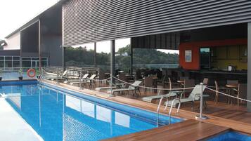 A swimming pool with lounge chairs and a bar area.