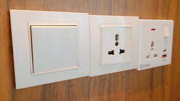 A wall-mounted electrical outlet with a switch, a standard electrical outlet with two sockets, and a USB port.