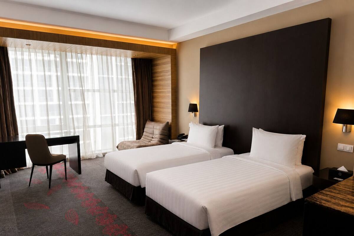 A hotel room with two beds, a desk, a chair, and a large window with curtains.